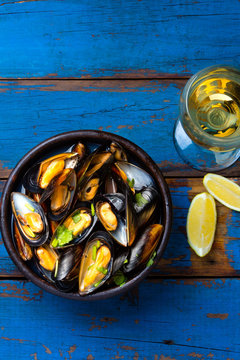 Mussels in clay bowl, glass of white wine and lemon