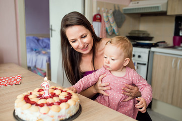 Obraz na płótnie Canvas Mother holding her baby daughter with birthday cake