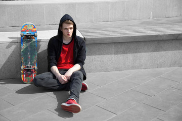 young skater resting on ground, skate board stands near © tafiphoto