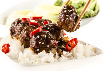 Asian meatballs with chinese sauce served with rice, steamed bok choy, sesame seeds and chili 