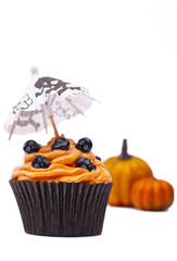 close-up shot of cupcake with skull and pumpkin in background.