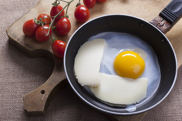 Fried eggs in a round pan wth cheese slices