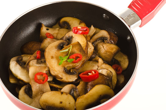 fried mushroom in fried pan with red pepper isolated on white