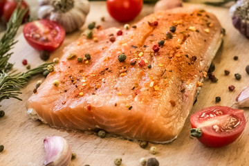 fresh raw salmon steaks with salt, peppers, lemon, tomatoes and dill on the rustic table
