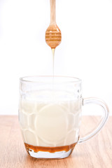 hot milk with honey dipper on white background..