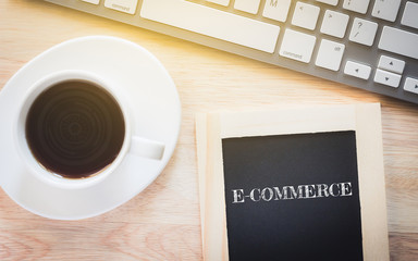 Concept E-COMMERCE message on wood boards. A keyboard and a glass coffee table.Vintage tone.
