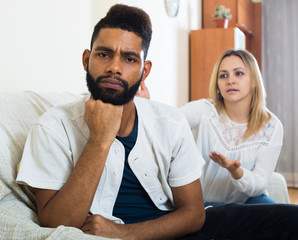 Blonde girl yelling at black boyfriend as quarreling indoors