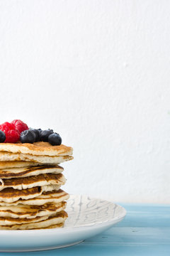 Pancakes with blueberries and raspberry on blue wood background 
