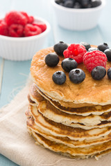 Pancakes with blueberries and raspberry on blue wood background 
