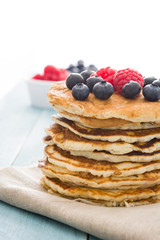 Pancakes with blueberries and raspberry on blue wood background 
