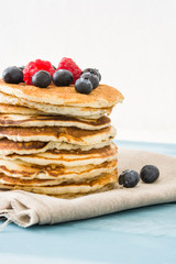 Pancakes with blueberries and raspberry on blue wood background 

