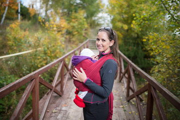 Mother holding her baby daughter, outside on wooden bridge