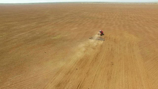 Aerial footage of vintage harvester, harvesting hay paddock in rows, around huge paddock in drought stricken dry land farming area of Australia and filling grain silo read for stock piling