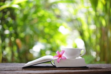 Notebook with flower and cup on wooden table 