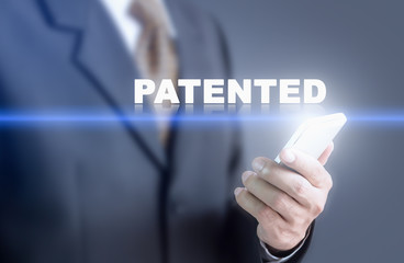 Businessman pressing hand PATENTED message on virtual screen. Can bring to the medium of your ad.