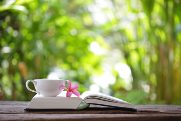 Notebook with flower and cup on wooden table