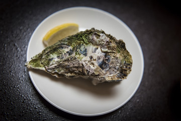 Closed oyster on a plate with a slice of lemon