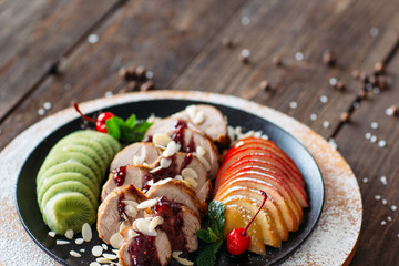 Food photography of baked veal with fresh fruits on wooden background. Baked meat with tropical fruits top view. Flat lay of creative food from baked veal on wooden table.  