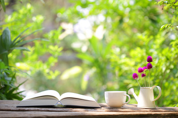 Notebook with white coffee cup and  globe amaranth in mini water pot  at outdoor