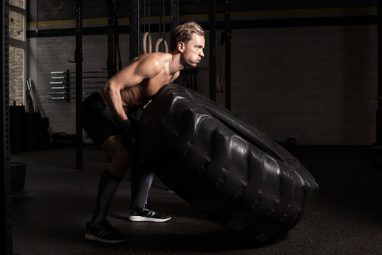 Strong and fit man pushing tire