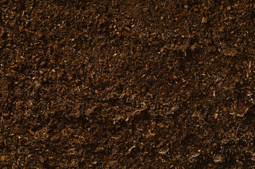 Brown, fertile, sandy soil ready for planting or fertilizing. Camera from above, top view. Natural background for advertisements.