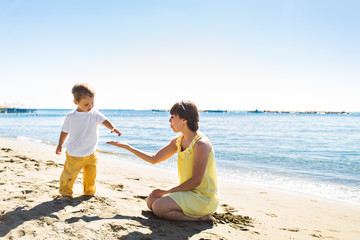 mother and son playing on summer tropical beach