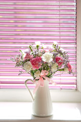 Bouquet of summer flowers in glass vase near the window