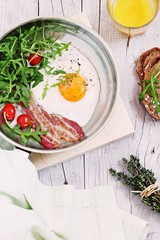 Fried egg with bacon,arugula and tomatoes. 