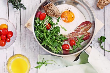 Fried egg with bacon,arugula and tomatoes. 