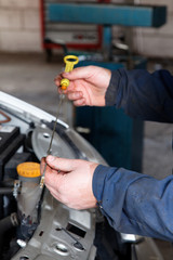 Fototapeta premium hands of an automechanic checking the oil level