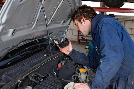 young auto mechanic checks a car in a garage