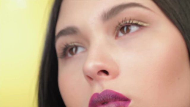 Girl blinks while visagist painting her lips