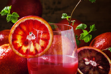 Red orange juice in a large glass, vintage wooden background, se