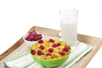  close up corn flakes bowl with raspberries bowl and milk on a tray