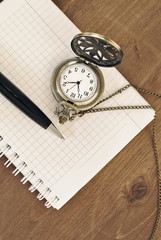 Notebook blank page, pen, vintage pocket watch on wooden background