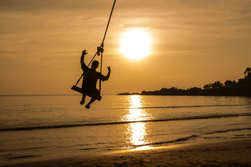 Happy man on a swing at sunset