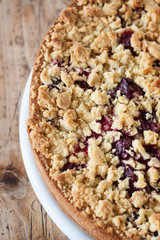 Homemade fresh sweet cherry crumble pie with whole wheat flour on a wooden table background ready to eat, closeup