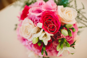 Two Golden wedding rings on bride's bouquet of roses