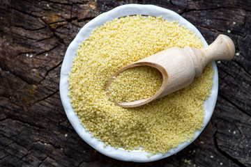 Raw Couscous on wooden background. Horizontal top view