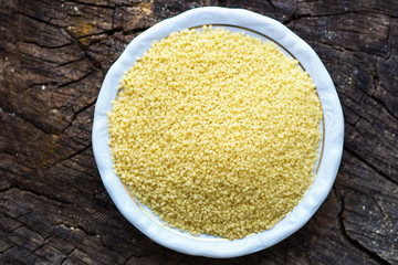 Raw Couscous on wooden background. Horizontal top view
