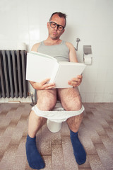 Man in restroom reading a book