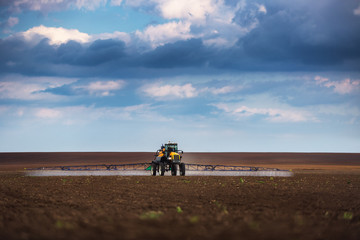 Farming tractor plowing and spraying on field