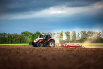 Farmer in tractor preparing land with seedbed cultivator