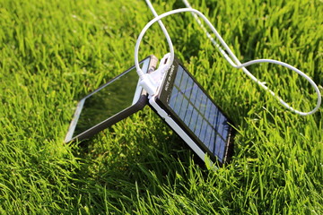 solar powerbank smartphone charging on a green grass