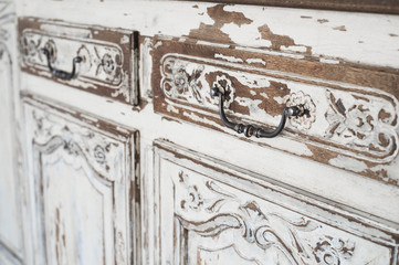 Close-up of ancient white commode bureau furniture with paint peeled off 