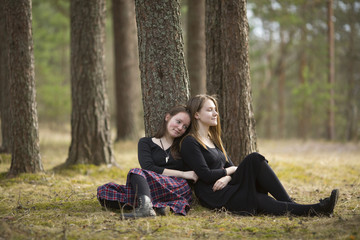 Naklejka na ściany i meble Teenage girls best friends sitting in the forest.