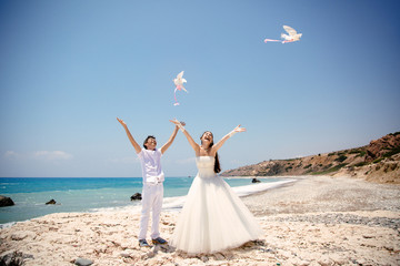 Fototapeta na wymiar Happy smiling bride and groom hands releasing white doves on a sunny day. Mediterranean Sea. Cyprus