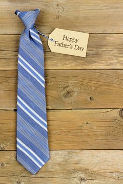 Happy Fathers Day gift tag with blue striped necktie on rustic wood background