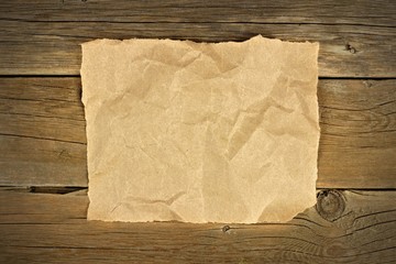Blank crumbled brown paper on a rustic wooden background
