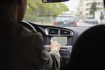 Mid adult man sitting in car, using gps